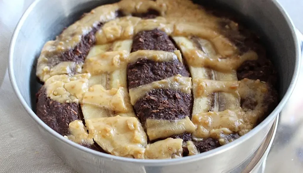 Chokladkaka med banan, toppad med jordnötssmör i en silvrig form och fotad av matfotograf från Rosell Media