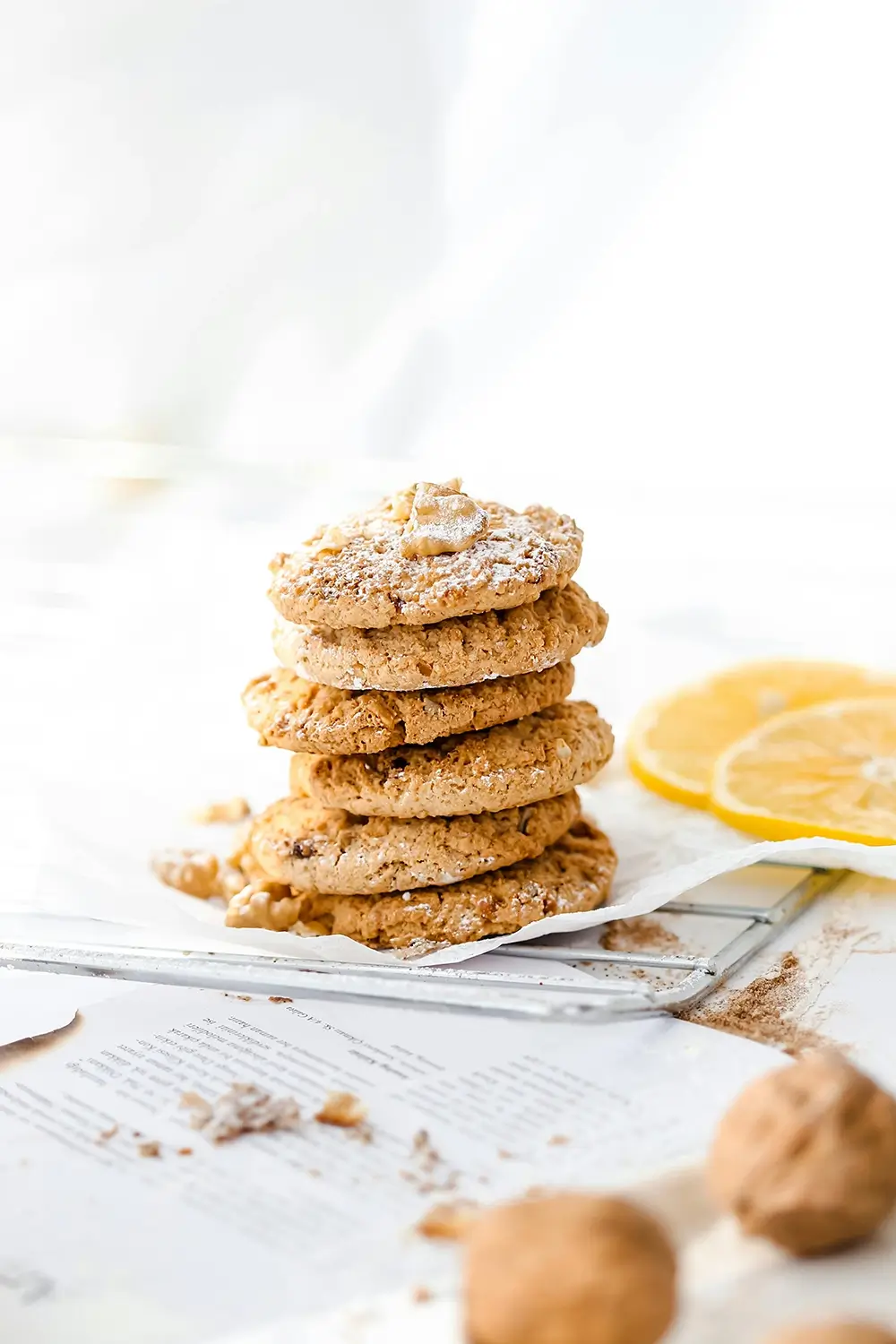Ljusa cookies eller kakor staplade på hög, ståendes på papper med tryfflar i förgrunden och citronskivor i bakgrunden
